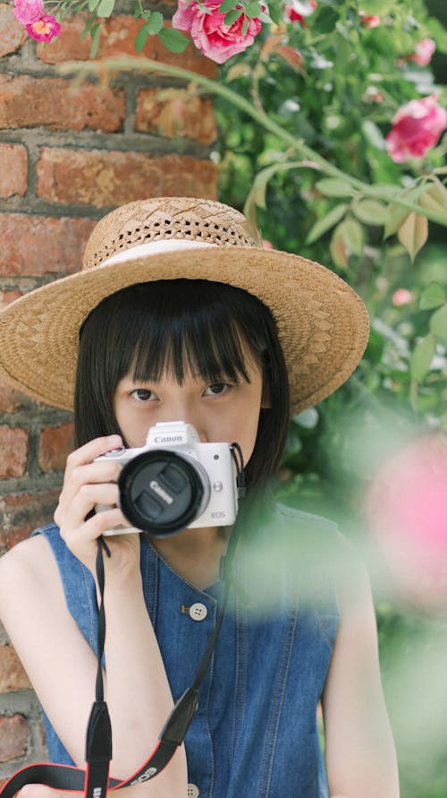 A girl with a camera in front of a wall
