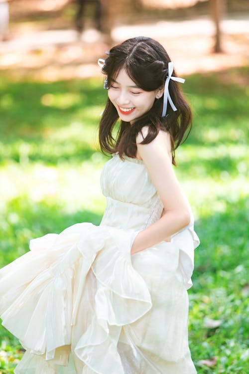 A young woman in a white dress is smiling