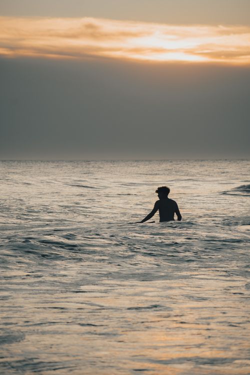 Silhouette of a Man Walking in the Sea at Dusk · Free Stock Photo