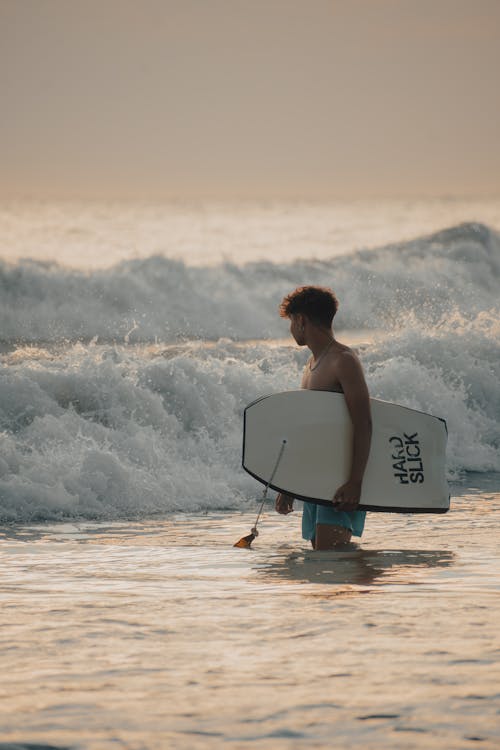 Surfer Standing in the Sea and Holding a Surfboard 