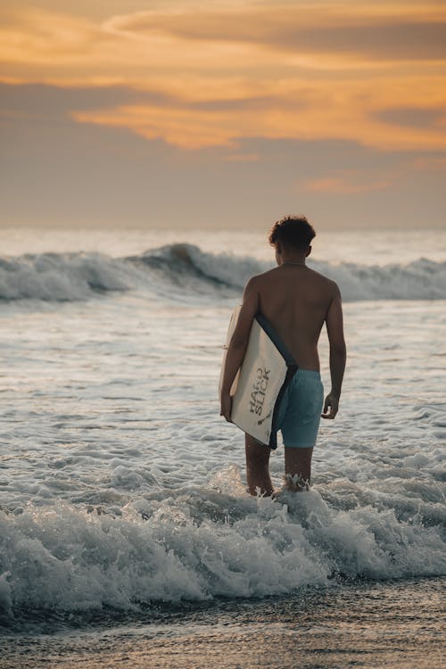Surfer Walking in the Sea with his Surfboard 