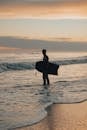 Silhouette of a Surfer Standing on the Beach with a Surfboard 