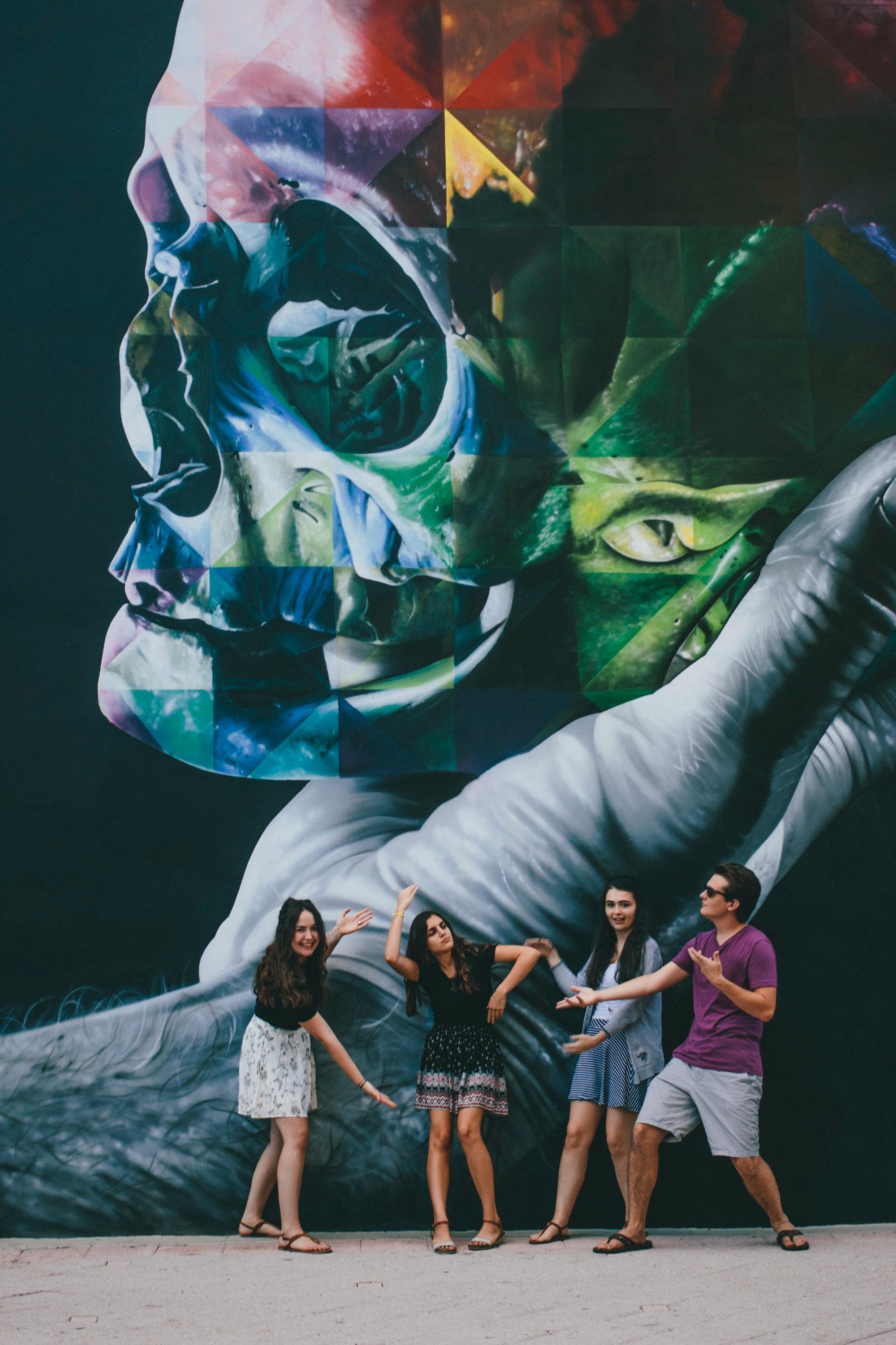 一群朋友在街头一幅充满活力的壁画前摆姿势，壁画上画着一个头骨