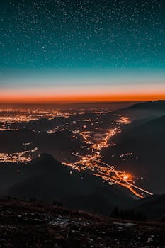 星空下，一座令人惊叹的城市景观被照亮，远处是山脉和闪闪发光的地平线