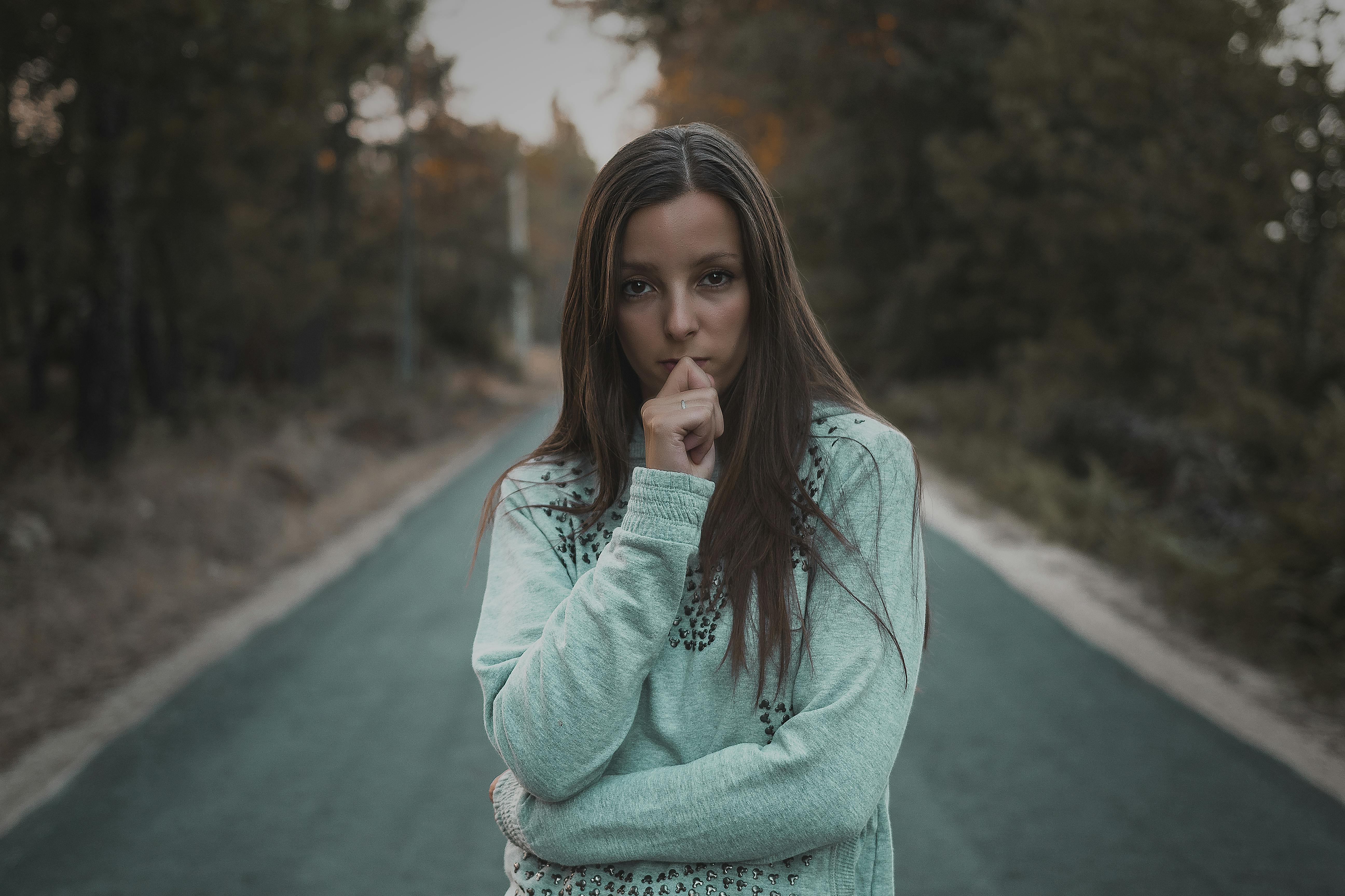 一位陷入沉思的女子，正静立在幽静的林间小道上