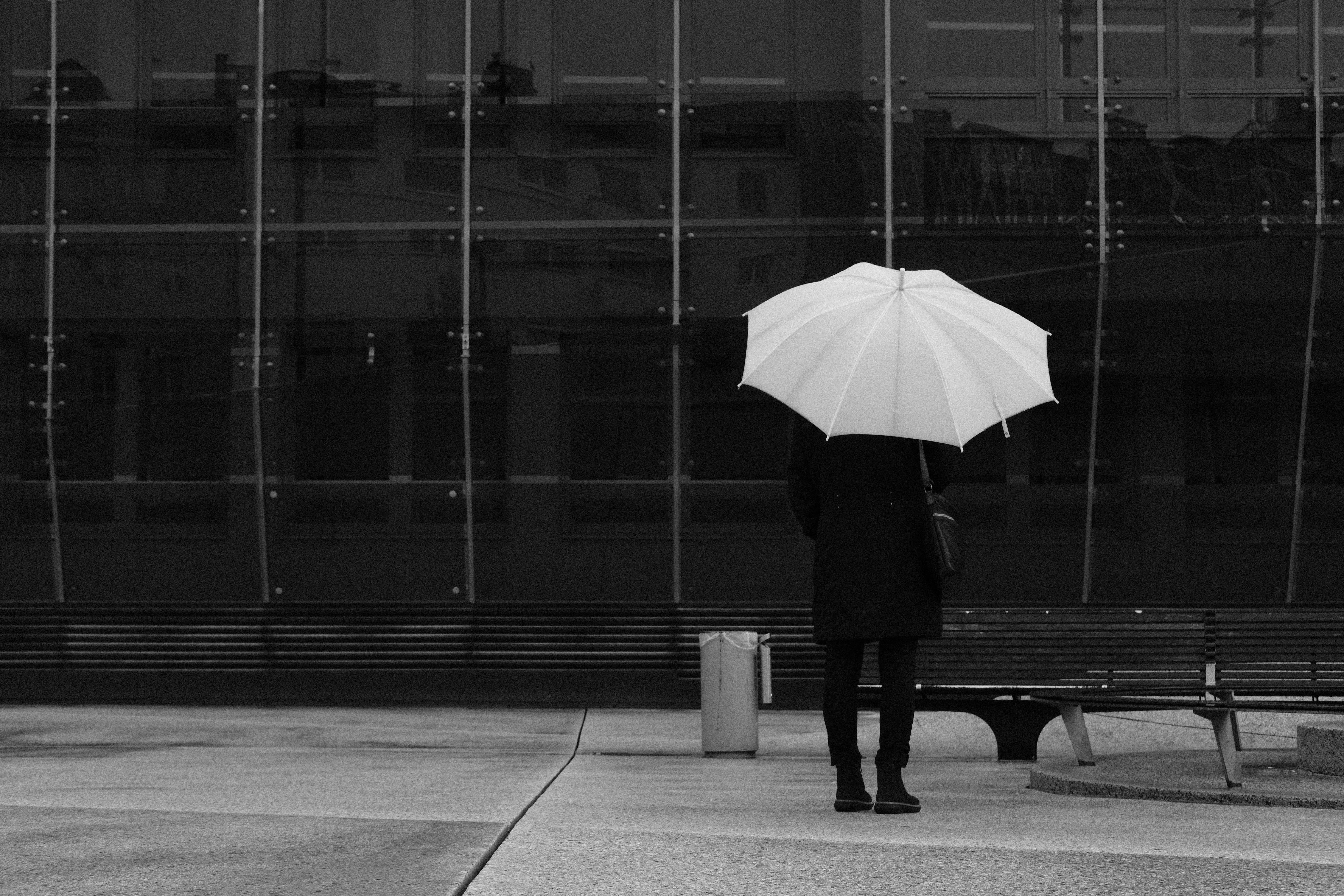 A person with an umbrella standing in front of a building