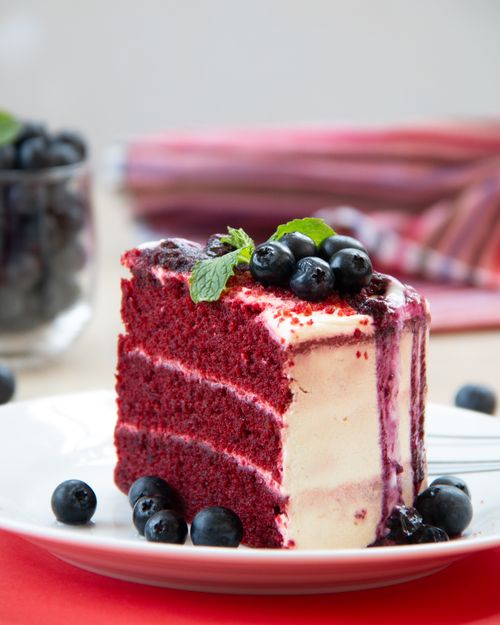 Free Close-up of a red velvet cake slice topped with blueberries and cream cheese frosting. Stock Photo