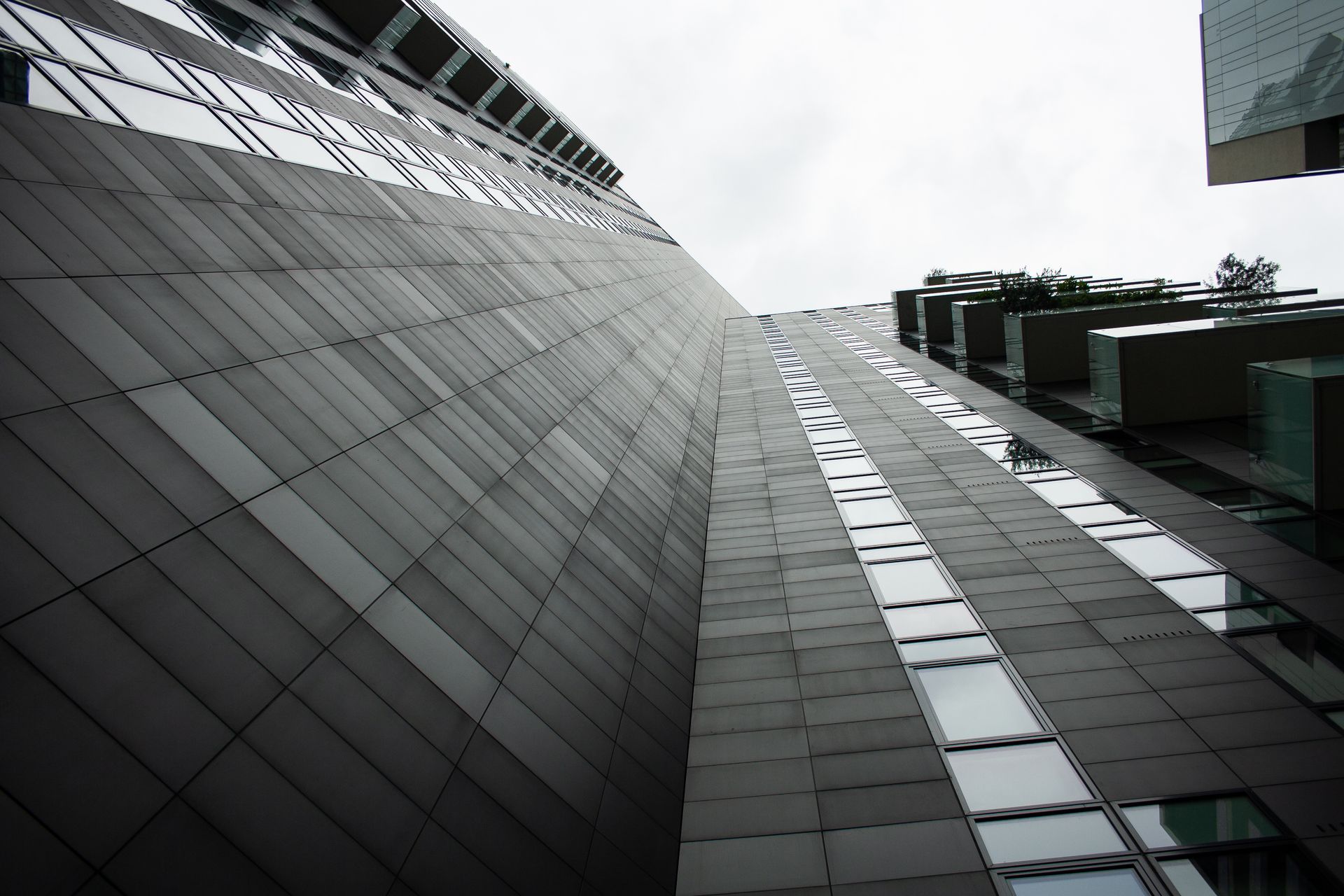 Low angle shot showcasing the modern architecture of a skyscraper with glass panels in Milano, Italy.