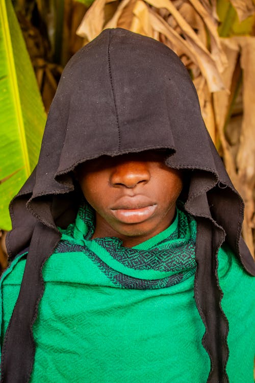A young african boy wearing a hooded cloak