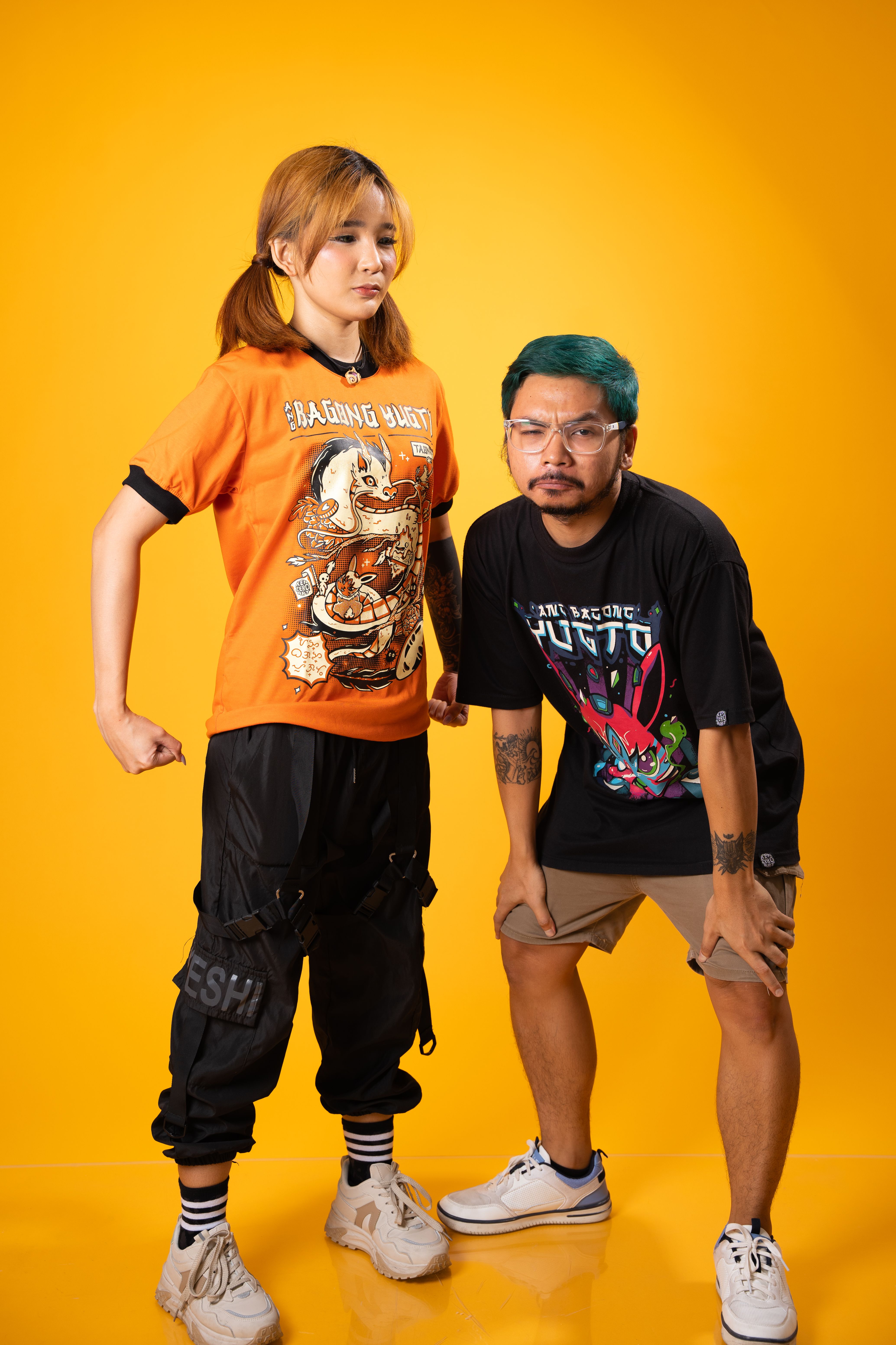 Two models in dynamic poses showcasing trendy fashion on a yellow background.