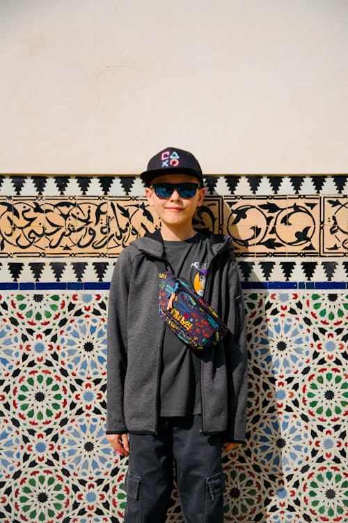 A boy standing in front of a wall with colorful tiles