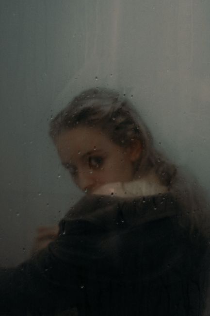 A mysterious portrayal of a woman seen through misted glass creating an ethereal and moody ambiance.
