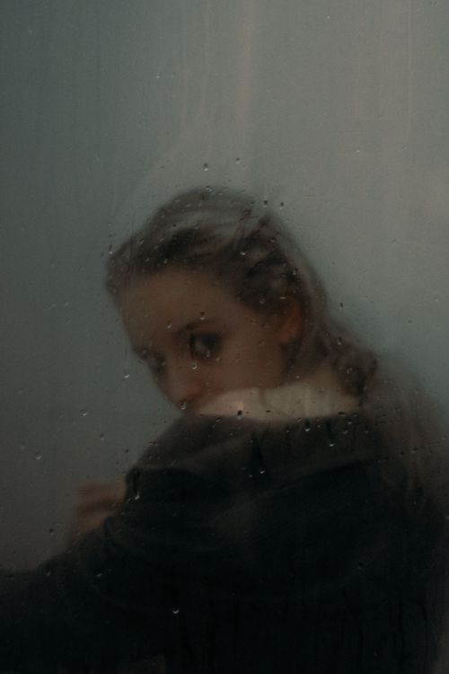 Free A mysterious portrayal of a woman seen through misted glass creating an ethereal and moody ambiance. Stock Photo
