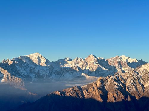 Free Majestic snow-covered mountain peaks under a clear blue sky captured at sunrise. Stock Photo