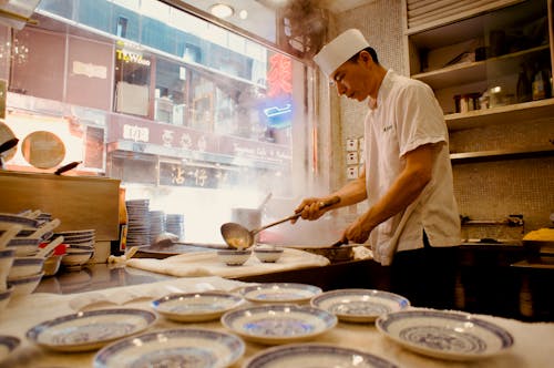 A man in a white chef's hat is preparing food