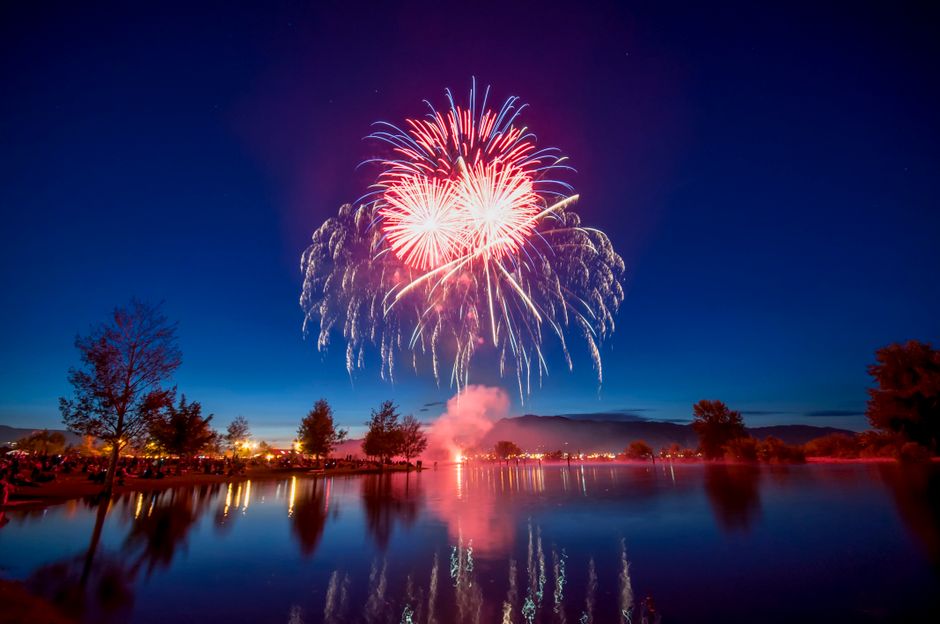 Colorful fireworks illuminate the night sky over a serene lake in Wenatchee, WA. Ideal for celebration themes.