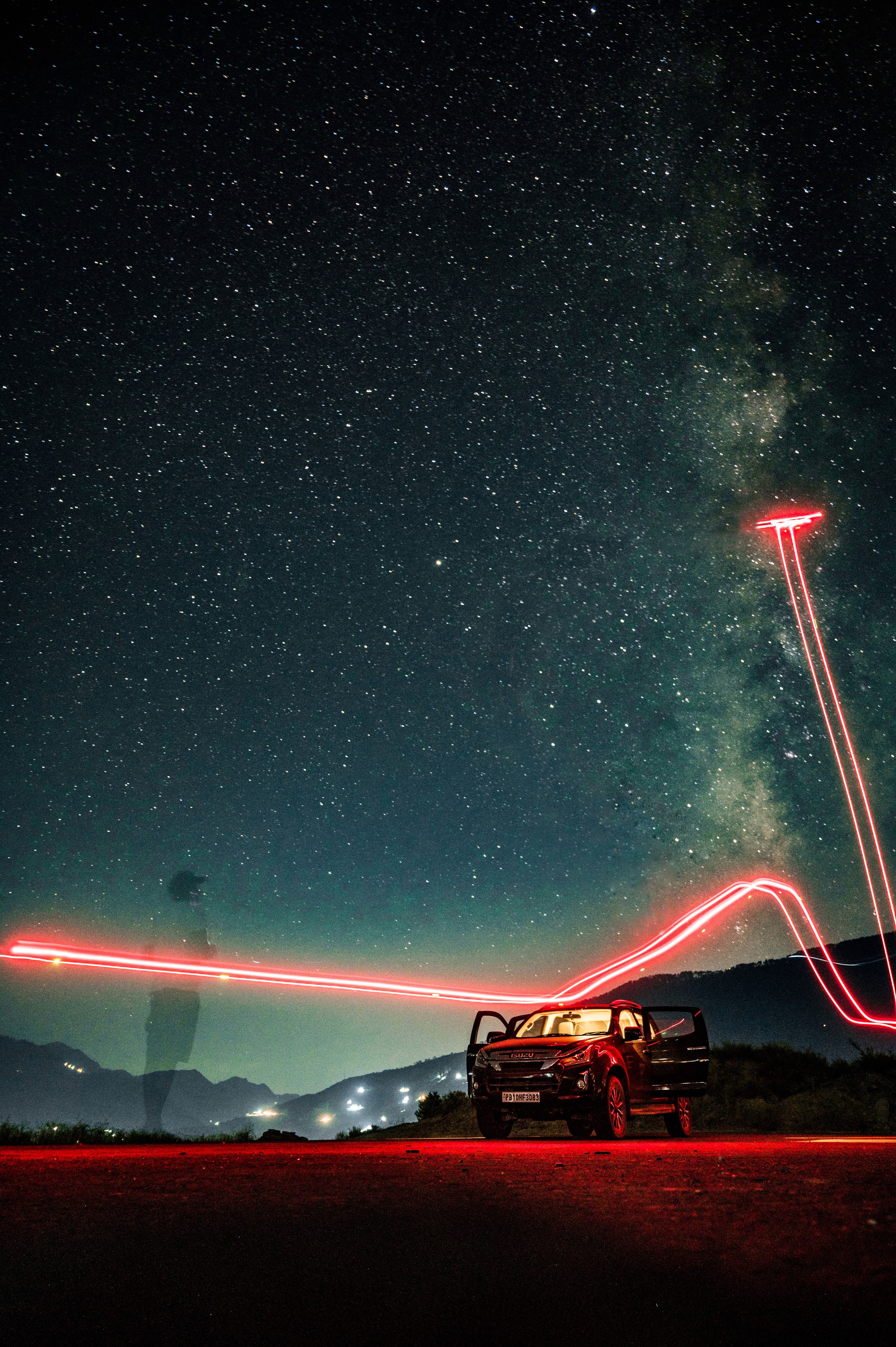 A mesmerizing night scene in Chamba, India showcasing a vehicle under a star-filled sky with captivating light trails.