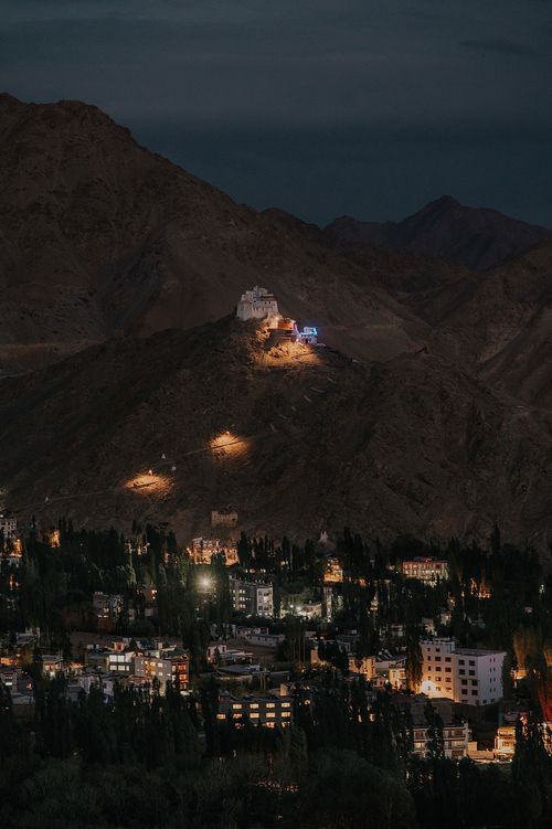 Free A night view of Leh city with illuminated hills and cityscape under a dark sky. Stock Photo