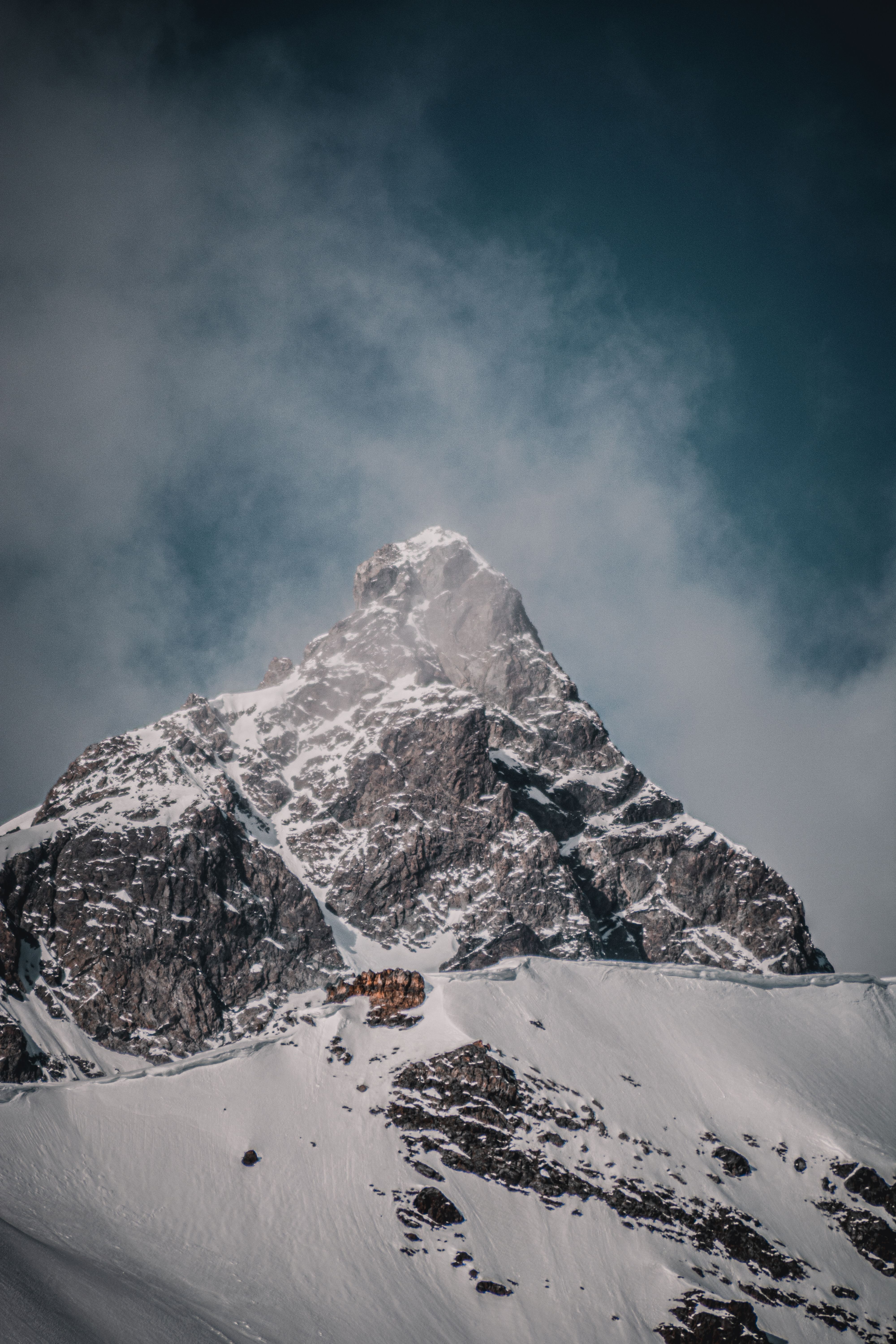 A mountain with a snow covered peak and a cabin · Free Stock Photo