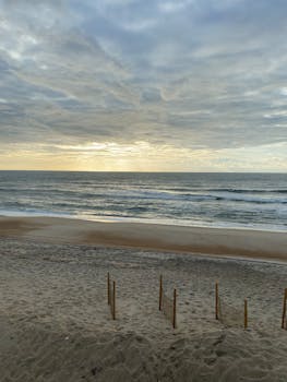 Peaceful seaside scene with gentle waves under a cloudy sky at sunset, ideal for relaxation concepts.