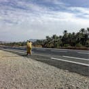 在摩洛哥乌利德奥特马内，一名身着传统服装的男子走在棕榈树掩映的道路上