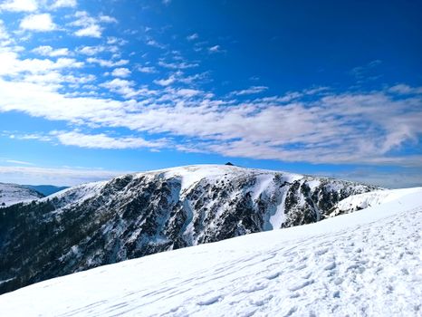 Breathtaking view of a snow-covered mountain peak under a bright blue sky in Sapois, Grand Est, France.