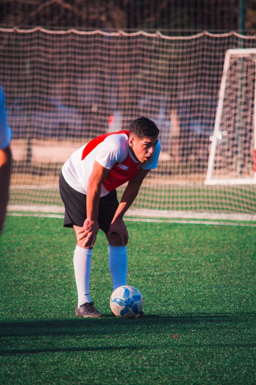 Free A tired soccer player resting on the field, showing fatigue and determination in a sports match. Stock Photo