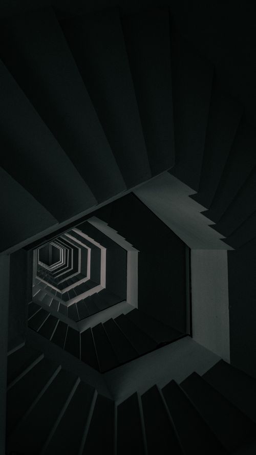 Free Dramatic view of a geometrical spiral staircase with dark shadows. Stock Photo