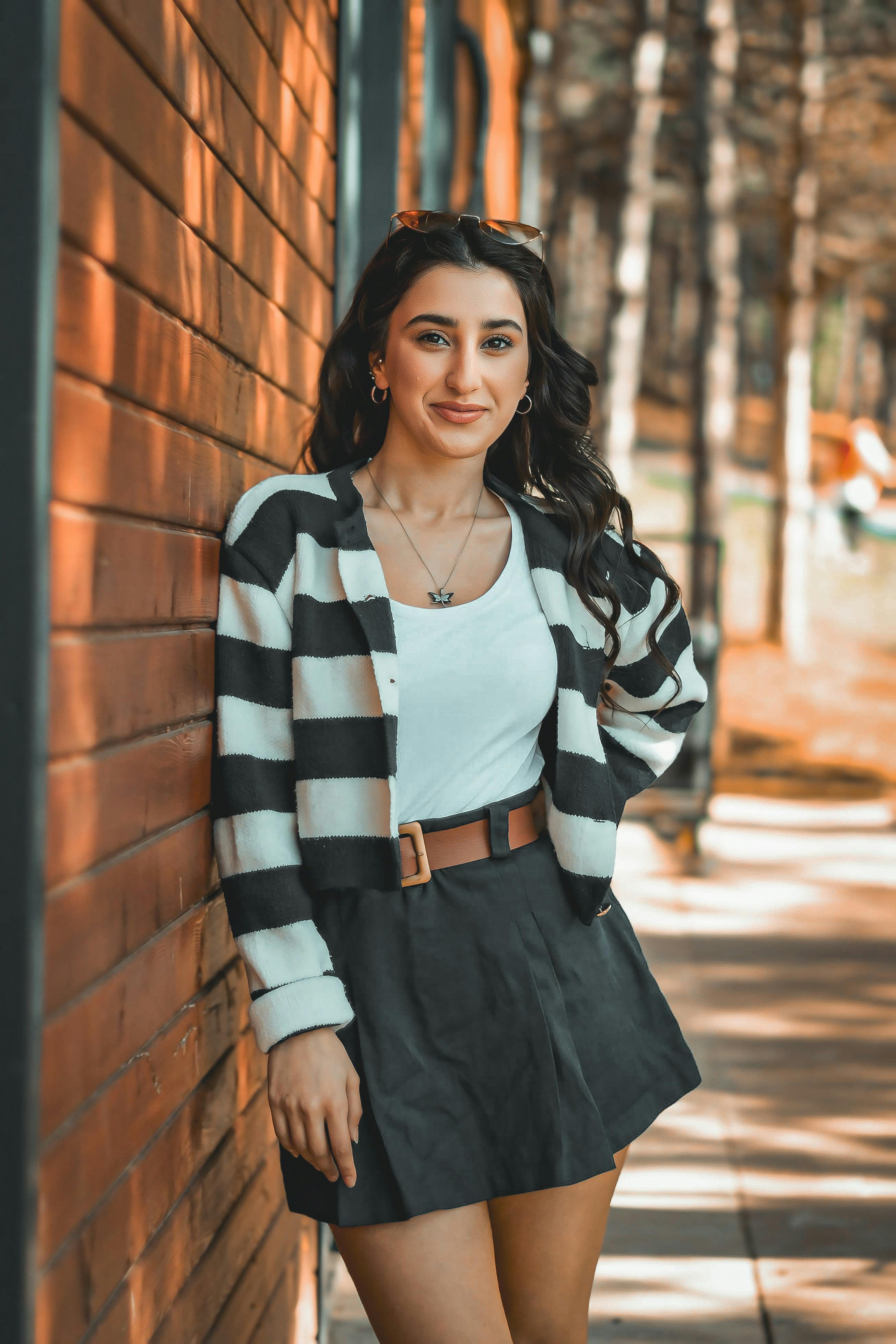 female model wearing a striped top and a mini skirt leaning on a brick wall