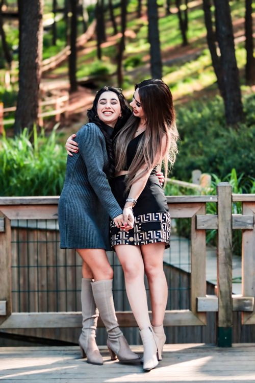 Free Two stylish women share a joyful hug in a sunny forest park. Stock Photo