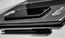 办公桌上的智能手机、笔记本电脑和笔的单色特写