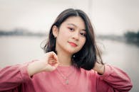 河边，一位穿着粉色毛衣的女子肖像散发着优雅和自信