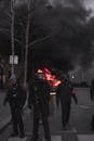 在夜间城市抗议活动中，全副武装的防暴警察面对街头火灾