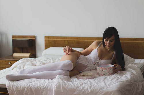 흰색 Monokini 침대에 누워있는 여자