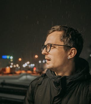 A warm-toned portrait of a man wearing glasses at night in Vitebsk, Belarus.