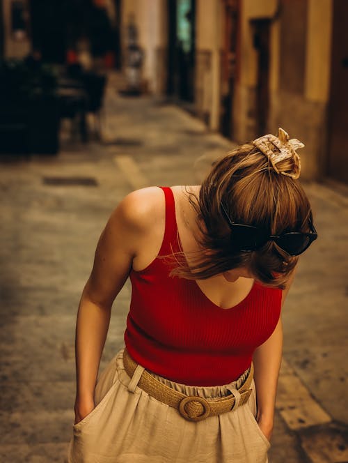 A woman in red top and white skirt walking down a street