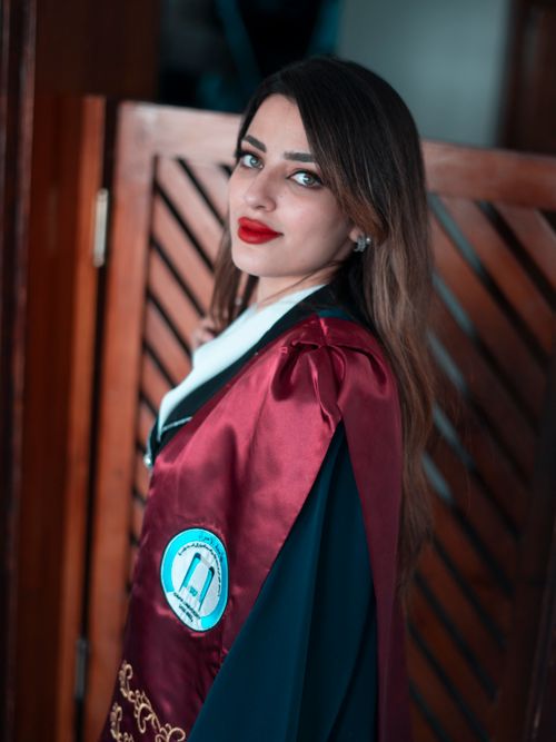 Free Elegant young woman in graduation gown, posing confidently in Baghdad setting. Stock Photo