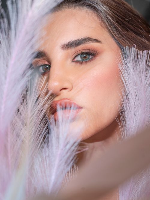 Free Elegant portrait of a young woman with striking eyes, surrounded by delicate feathers, conveying beauty and grace. Stock Photo