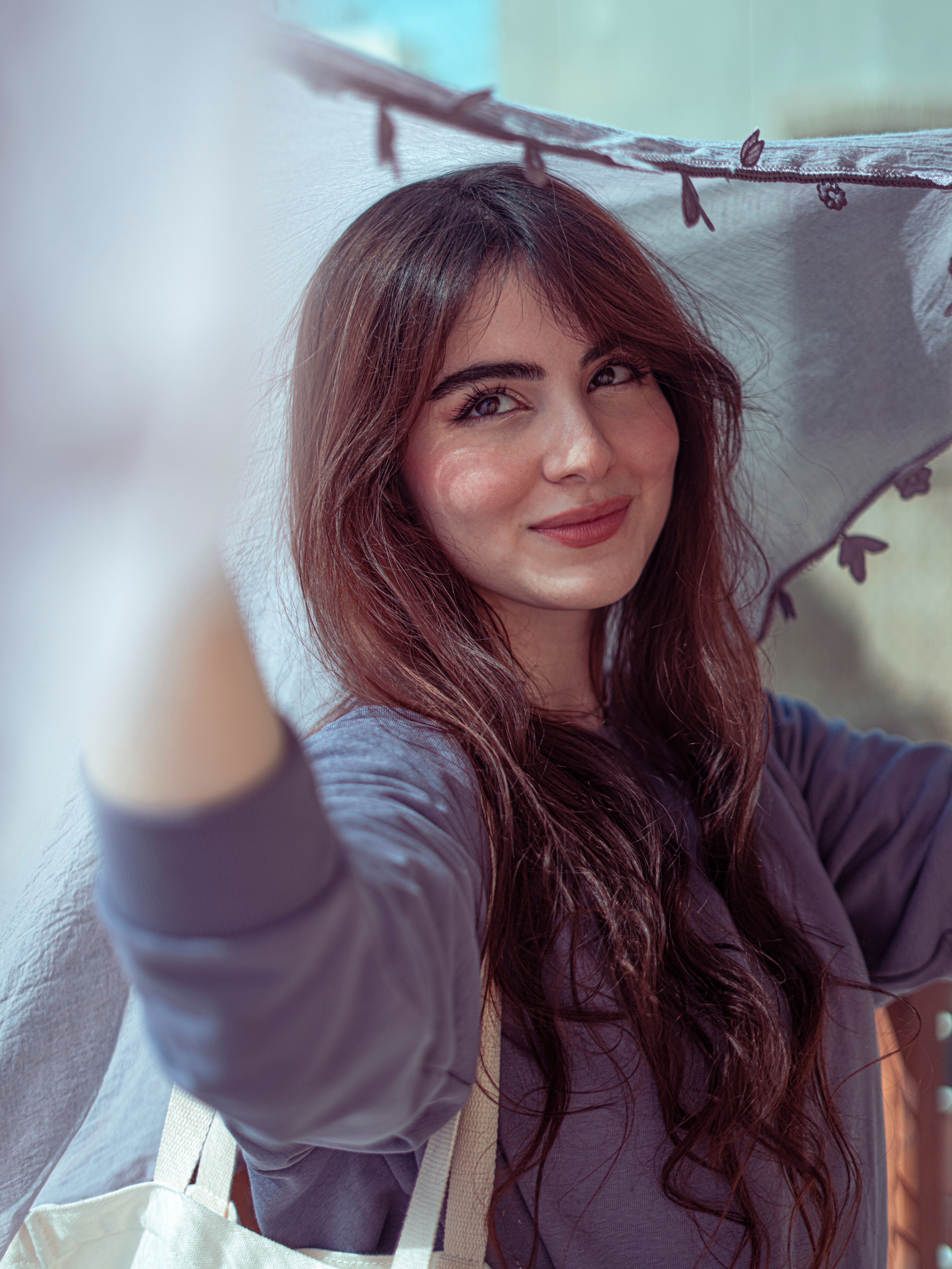 Portrait of a smiling Middle Eastern woman holding blue fabric with a natural background in Baghdad.