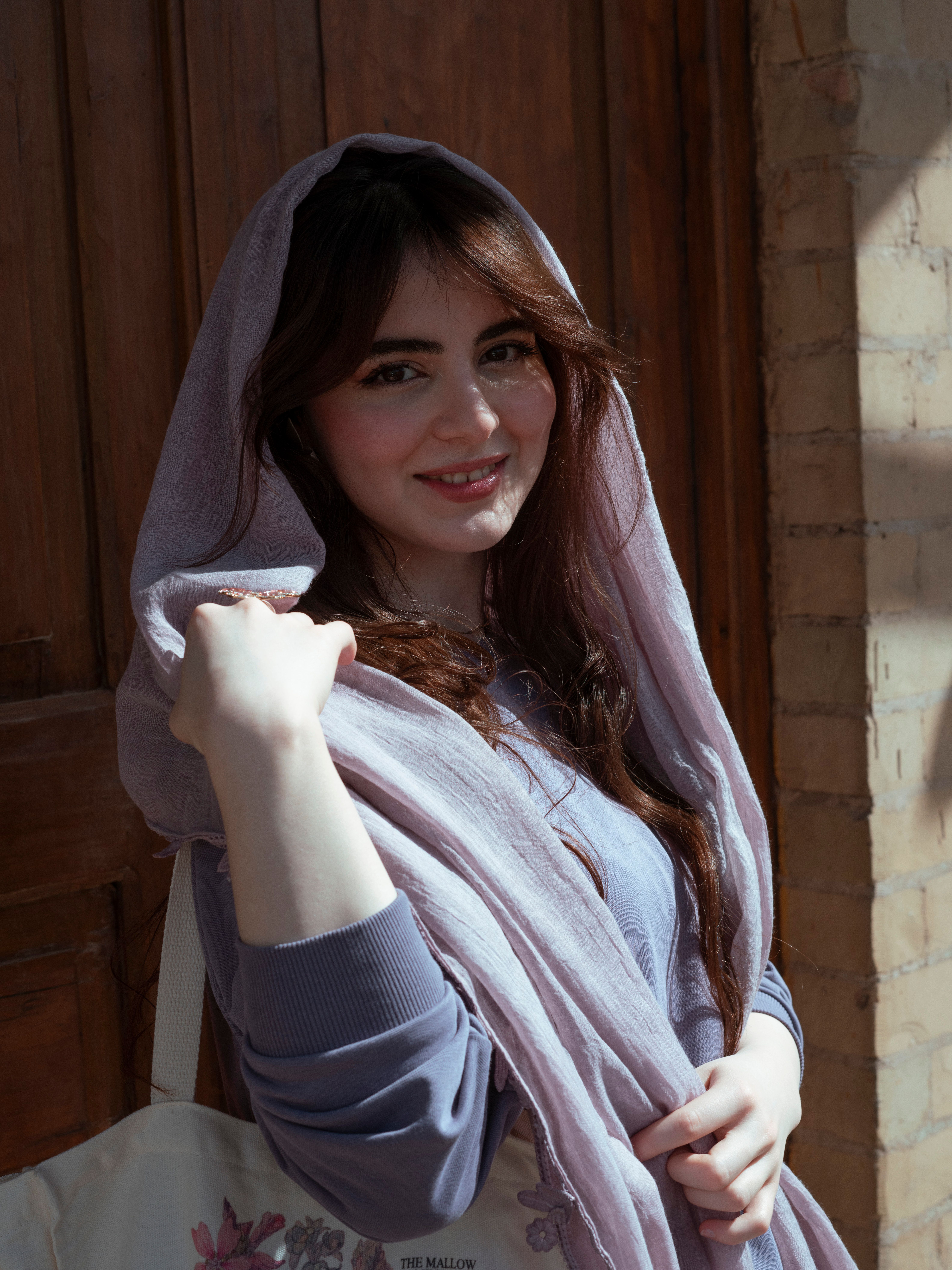 A woman with a headscarf smiles confidently in an outdoor setting in Baghdad.