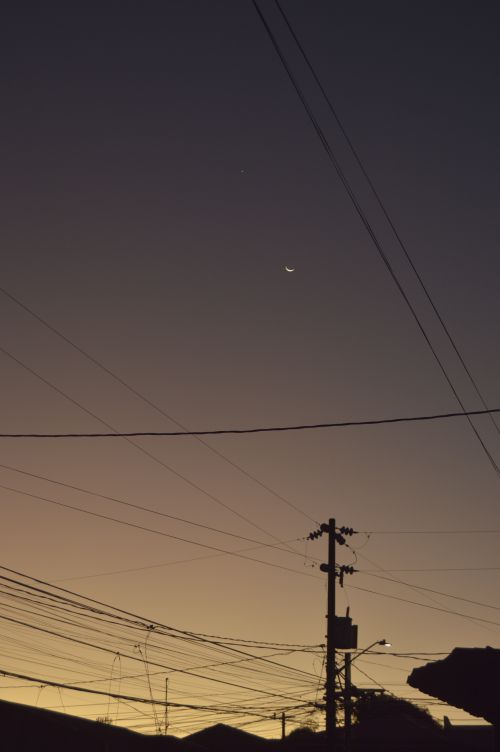 Free Silhouette of power lines and crescent moon at dusk in urban Manila. Stock Photo