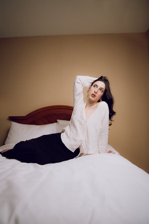 A woman is laying on a bed in a white shirt