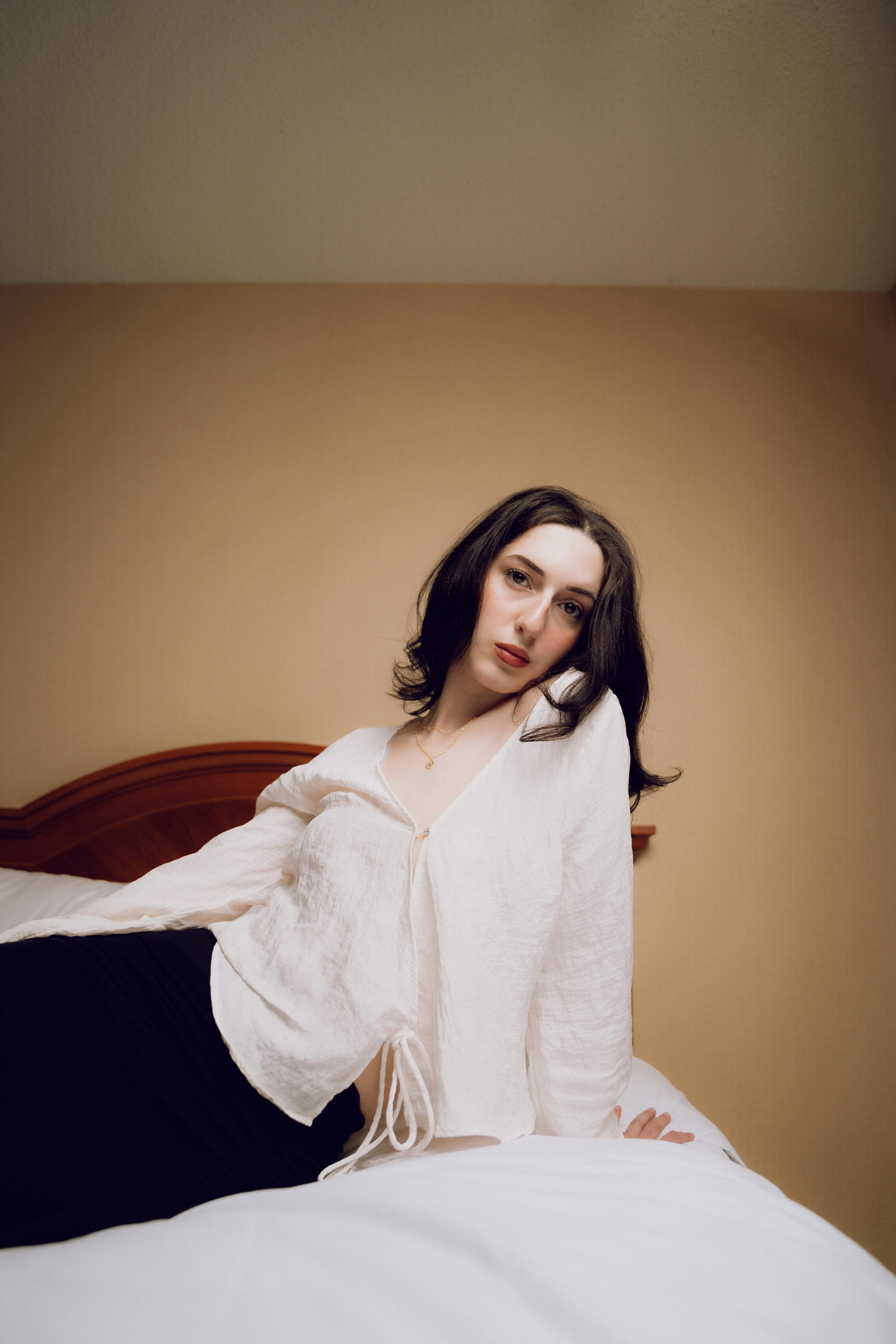 A woman in a white shirt and black skirt is laying on a bed