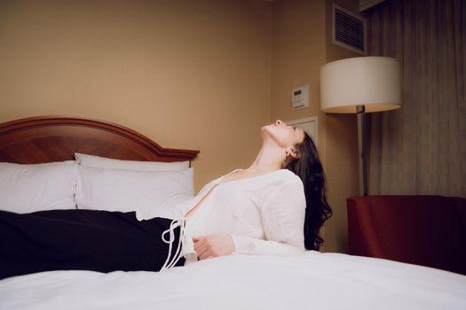 A woman laying on a bed with her head in the air