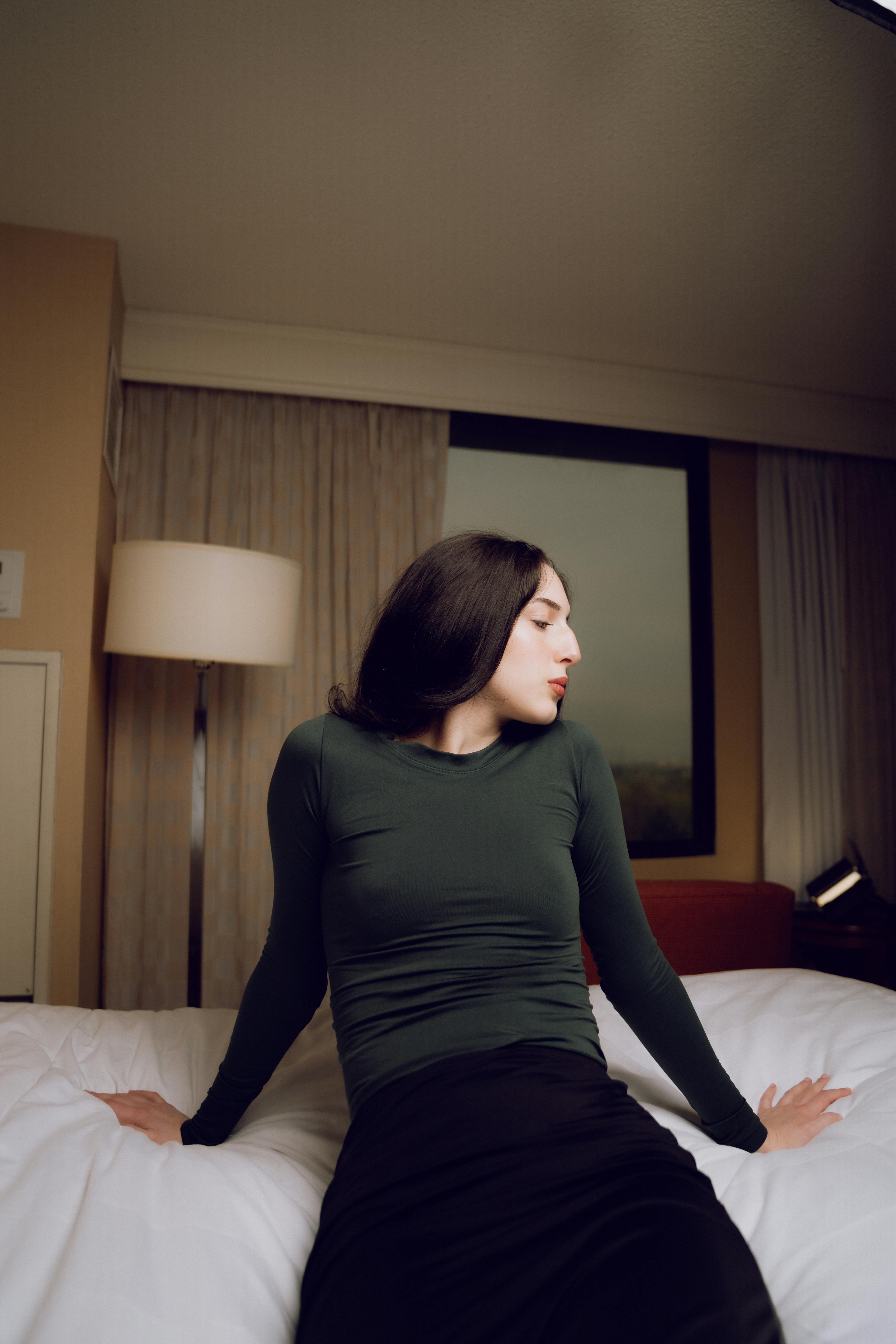 a woman in a green shirt sitting on a bed