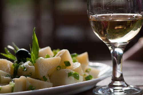 Glass of Wine Near Steamed Sliced Potato Dish