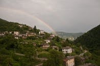 郁郁葱葱的山上坐落着一个迷人的村庄，风景上方有一道美丽的彩虹