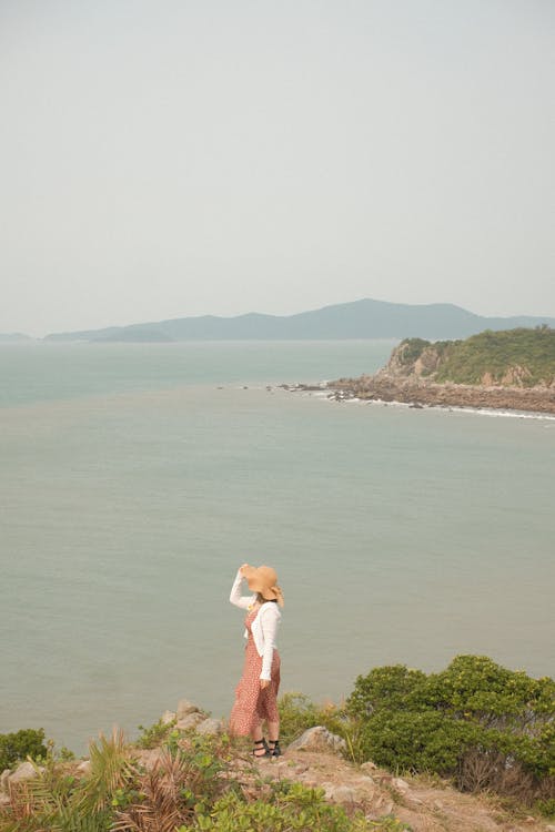 Free Woman Wearing a Sun Hat Standing On a Cliff Stock Photo