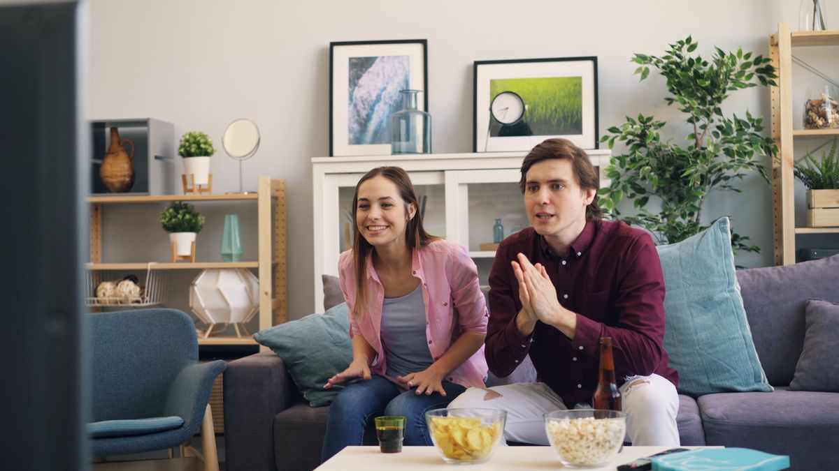 Couple relaxing on a sofa while watching television at home, representing everyday entertainment in Halifax