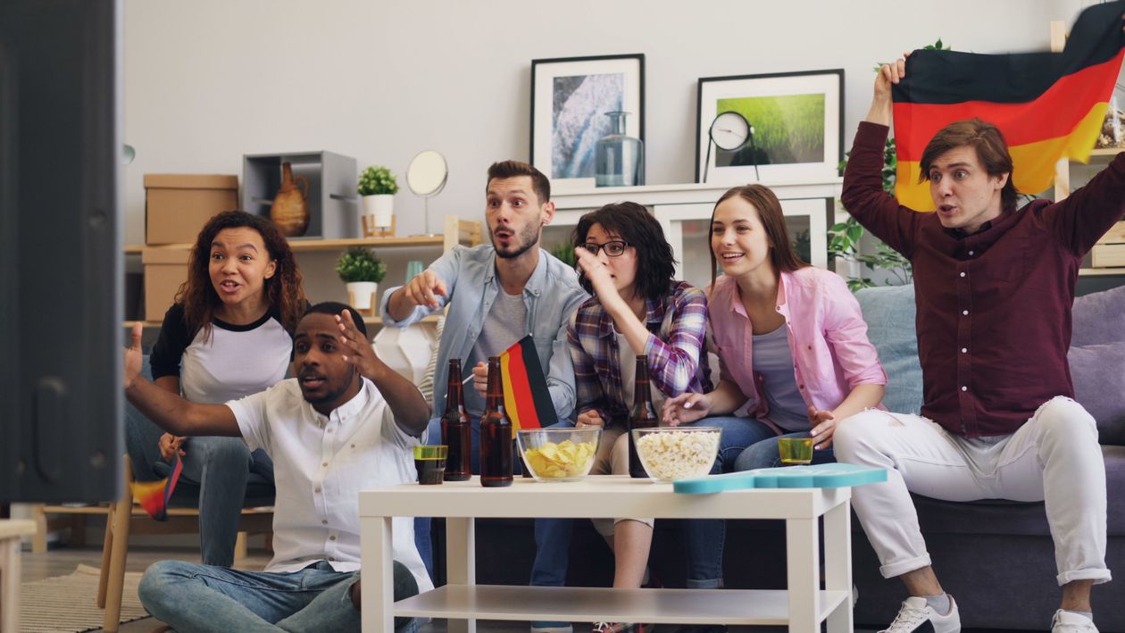 A diverse group of friends excitedly watching a live sports game together at home